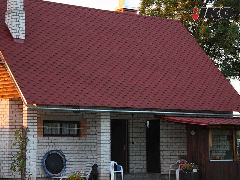 Ķieģeļu māja ar sarkanu bitumena šindeļu jumtu