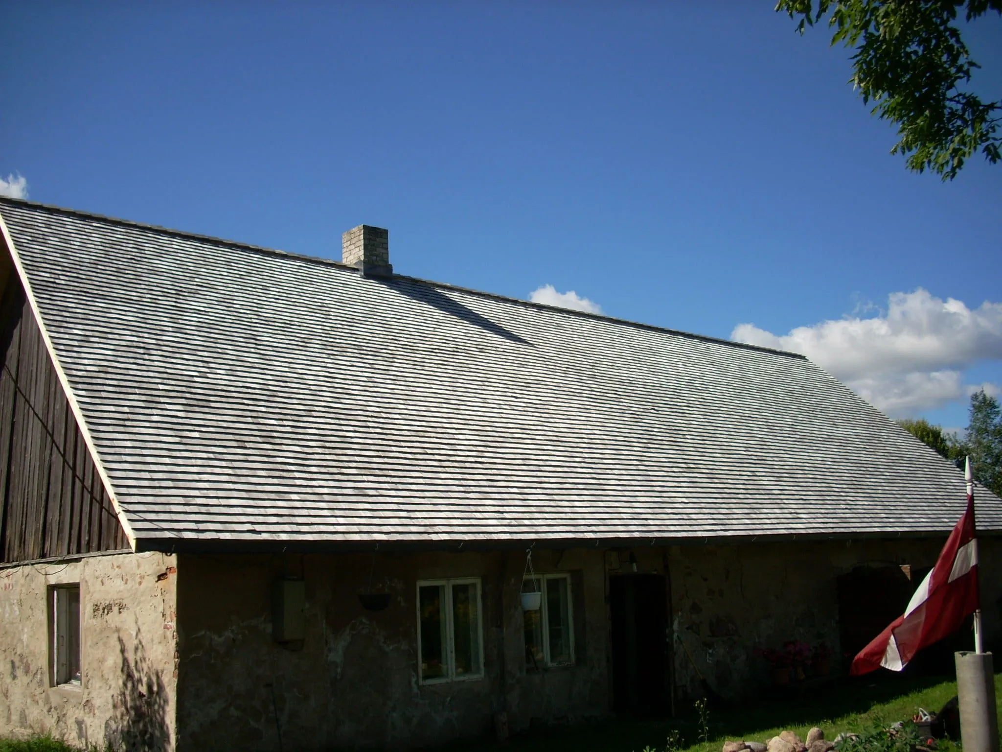 Akmens ēka ar sirmu koka šindeļu jumtu